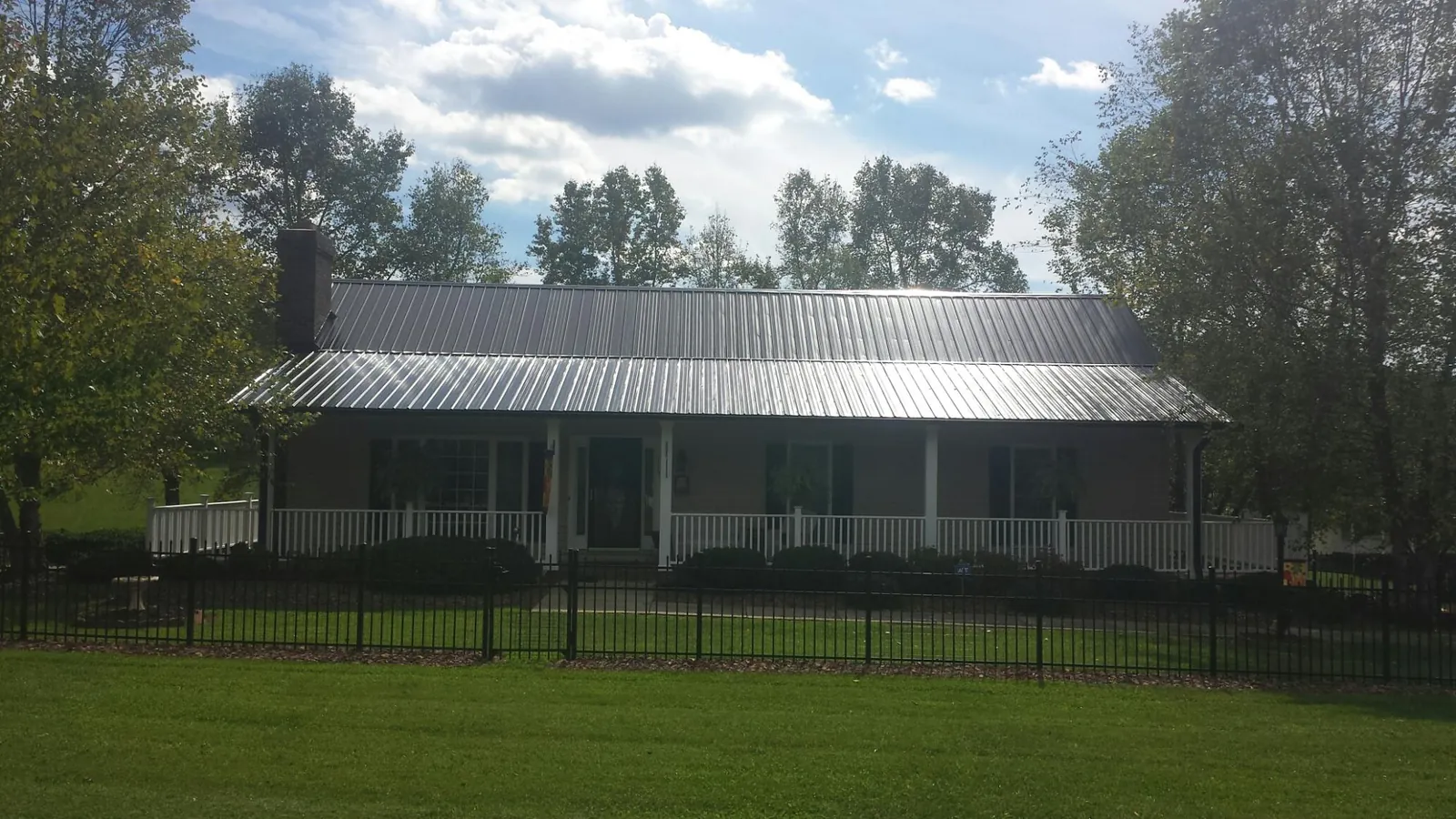 Gray metal roof on a brick ranch with a full width front porch — Gutter Guard Installation work by our crew in Jersey City