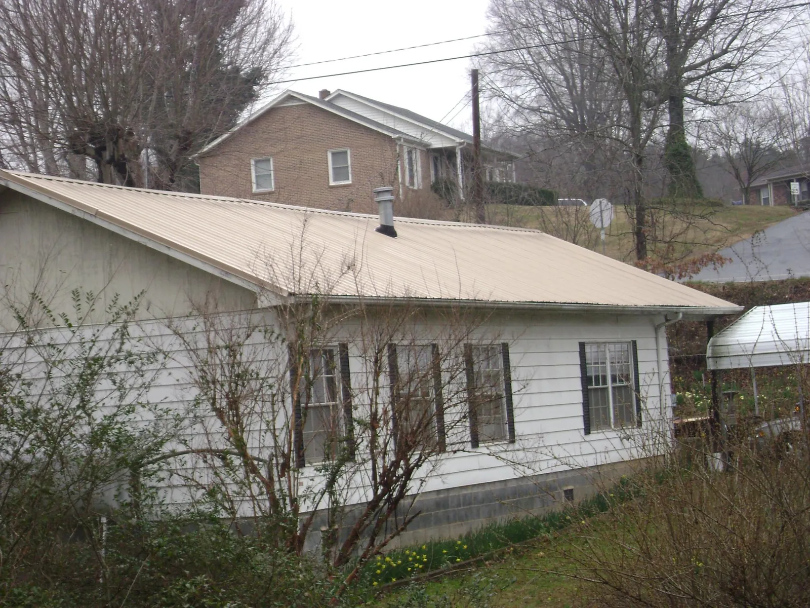 Tan metal roof on a white sided house set into a hillside — Commercial Roofing by Roofing Brothers in Jersey City