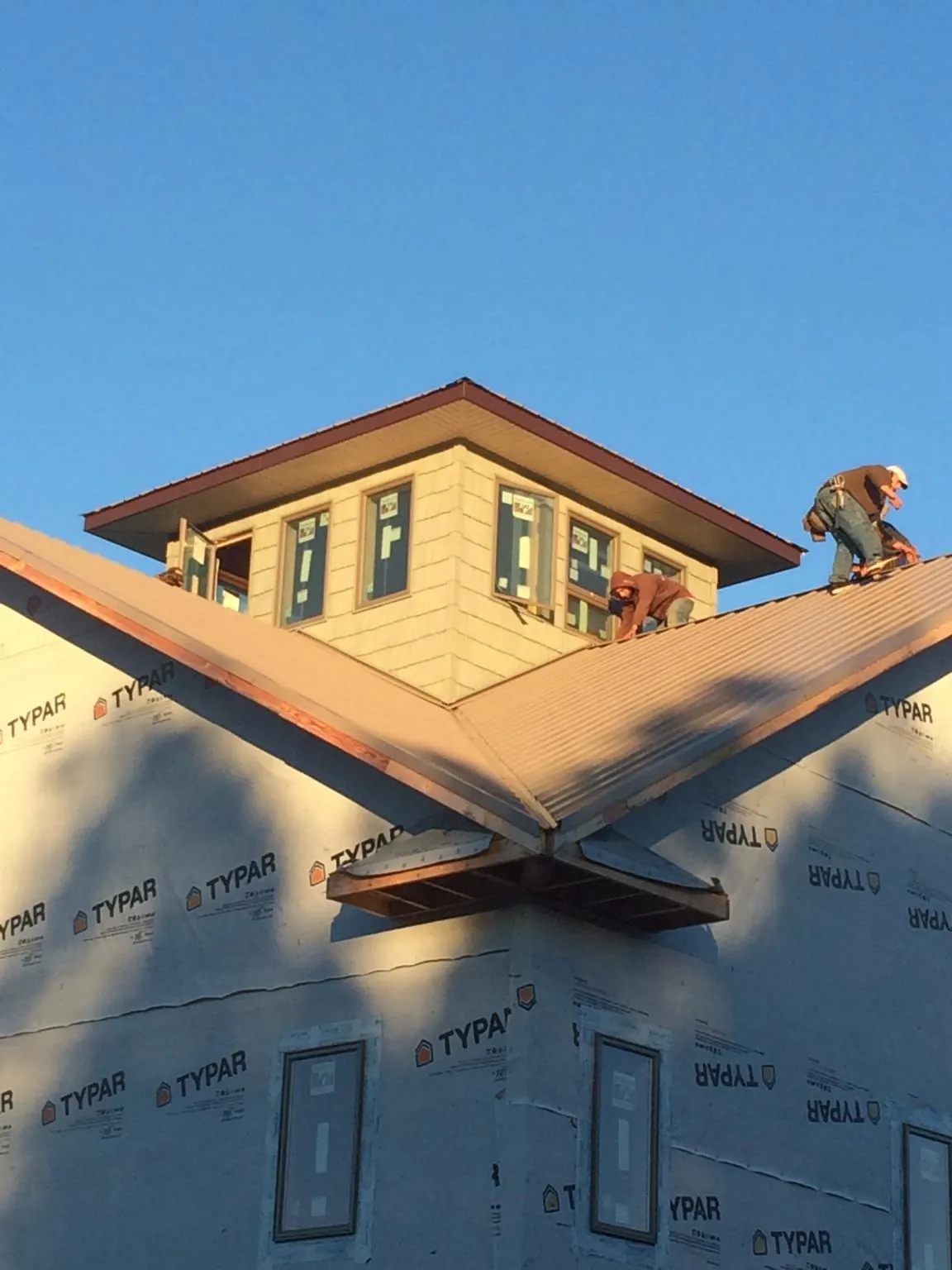 Roofers working around a rooftop cupola on a new metal roof at sunset — Roof Waterproofing in Jersey City by Roofing Brothers